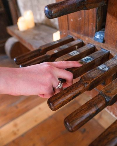A hand rests on a wooden object, echoing the centuries-old craftsmanship found in St. Nicholas’ Collegiate Church.